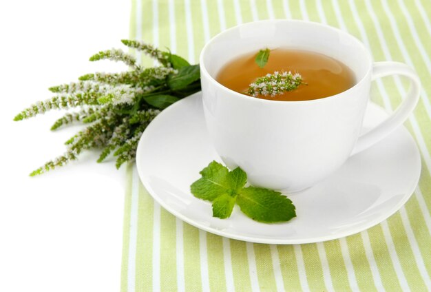 Tazza di tisana con fiori di menta fresca isolati su bianco