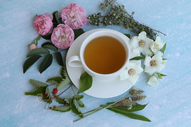 tazza di tisana con fiori estivi su sfondo blu