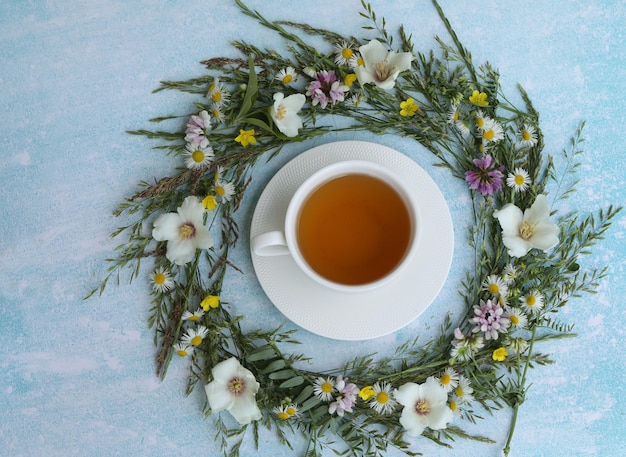 tazza di tisana con fiori estivi su sfondo blu