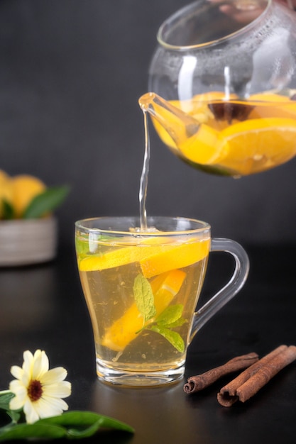 Tazza di vetro con tisana di frutta su sfondo nero. Tè salutare alla calendula