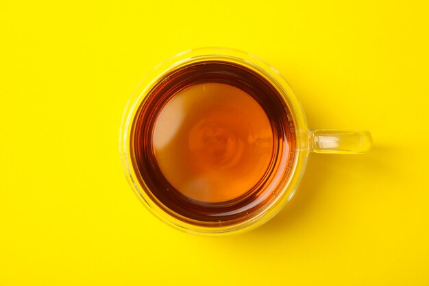 Tazza di vetro del tè di camomilla su giallo