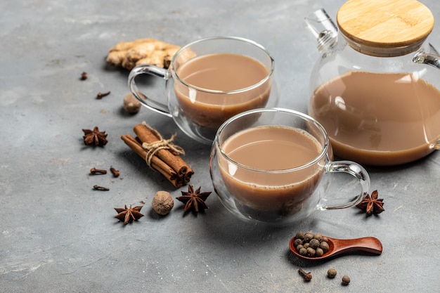 Tazza di vetro del tradizionale tè indiano masala chai con latte e spezie su sfondo grigio banner menu ricetta posto per testo vista dall'alto