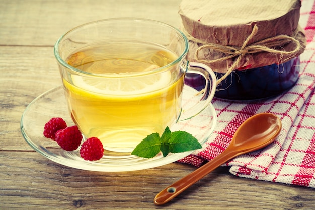 Tazza di vetro di tè verde con un piattino e la fetta di limone