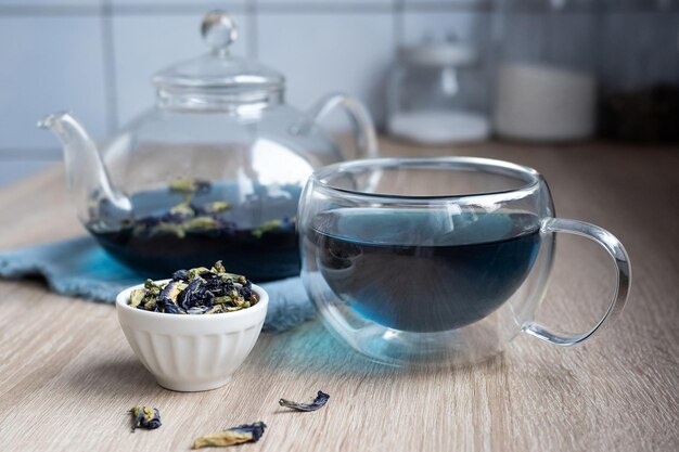 Tazza di vetro e teiera con anchan dal fiore di pisello farfalla, tè blu alle erbe sul tavolo della cucina.