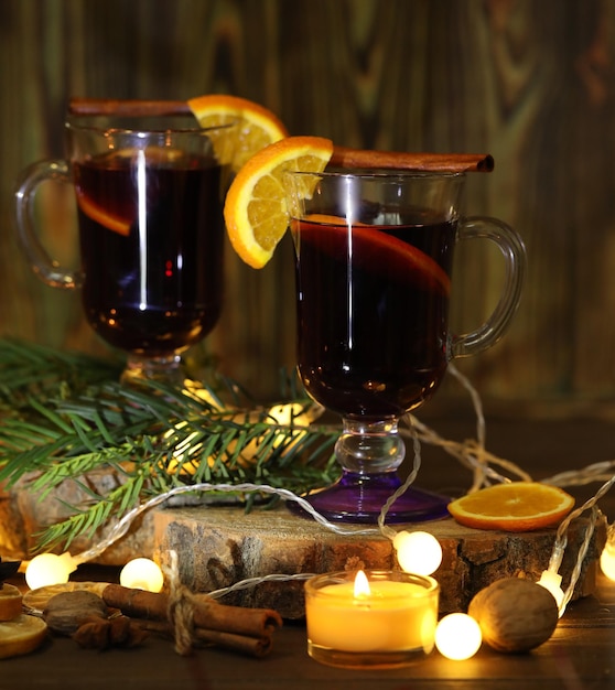 tazza di vin brulè con decorazione e candele su fondo di legno scuro