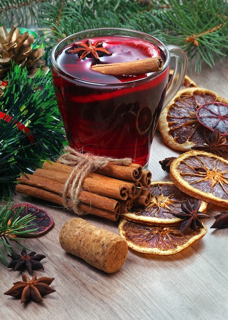 tazza di vin brulè, spezie e agrumi secchi su un tavolo di legno.