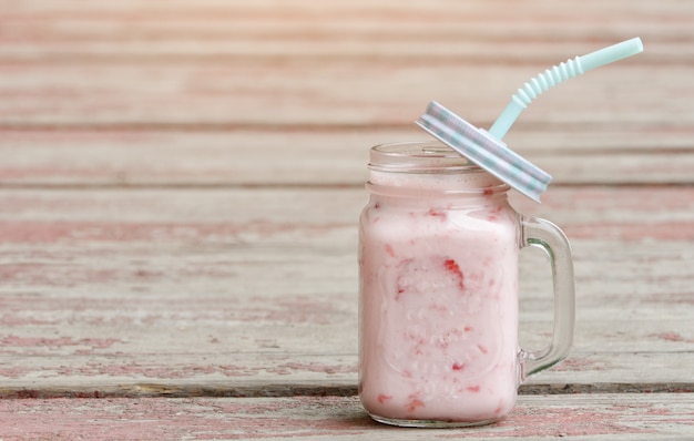 Tazza di yogurt e fragole su tavole di legno vintage sfondo rosso