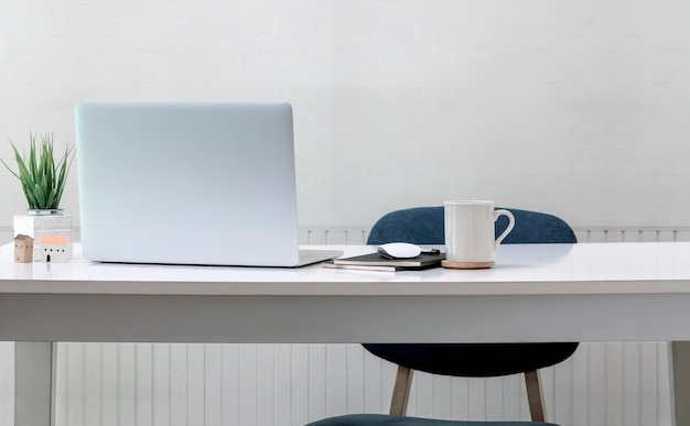 Tazza e computer portatile bianchi sulla tavola di legno bianca