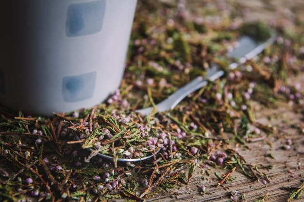 Tazza e cucchiaio con tè fiorito su fondo in legno