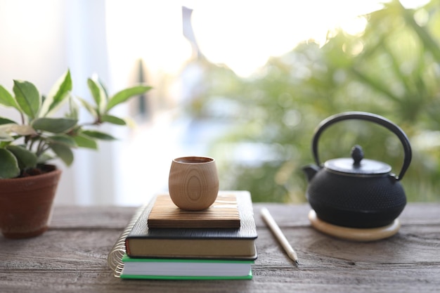 Tazza e libri di legno di bambù con la vecchia teiera di metallo nero