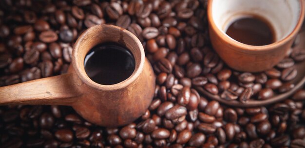 Tazza e pentola di caffè dell'argilla sui chicchi di caffè