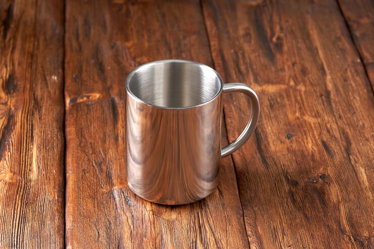 Tazza in acciaio inossidabile su un vecchio tavolo di legno