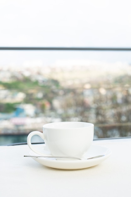 Tazza in ceramica bianca con piattino sul tavolo da esterno