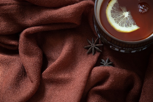 Tazza in ceramica di tè caldo al limone, anice stellato, su una stola di lana marrone. Vista dall'alto