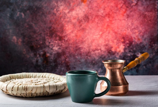 Tazza in ceramica e Turk in rame su sfondo rosso Attributi del caffè Fare il caffè Vista frontale