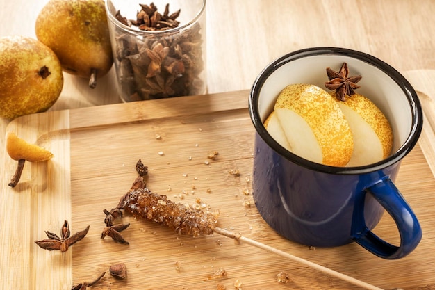 Tazza in metallo smaltato blu con stelle di anice caramello di zucchero di canna e frutta su legno di bambù