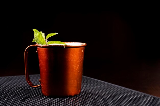 Tazza in rame di bevanda al mulo di Mosca con foglie di menta vista dalla parte anteriore del bancone del bar