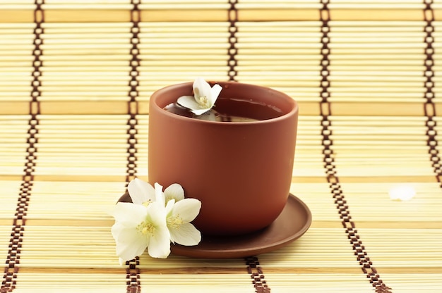 Tazza in terracotta con tè verde e fiori di gelsomino