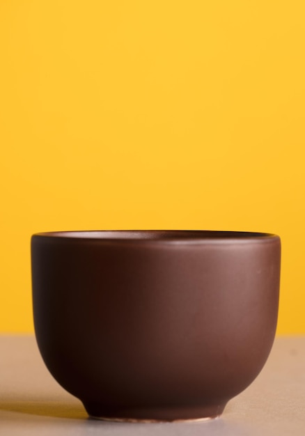 Tazza marrone con caffè o cioccolato con sfondo giallo