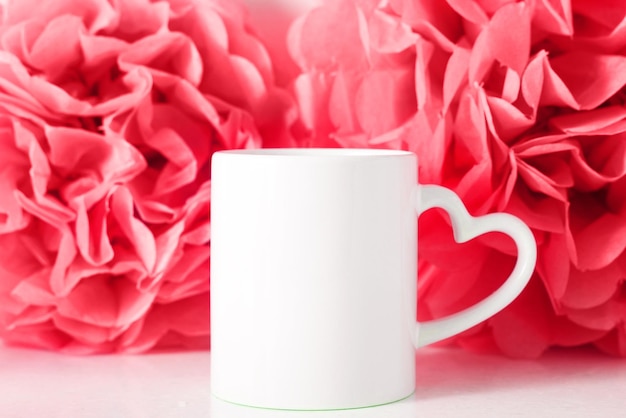 Tazza mockup bianca su sfondo di fiori di carta rosa