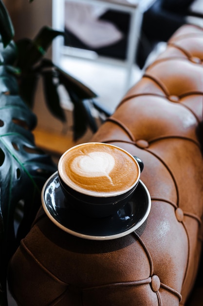 Tazza nera di cappuccino con latte art su fondo in legno Bella schiuma