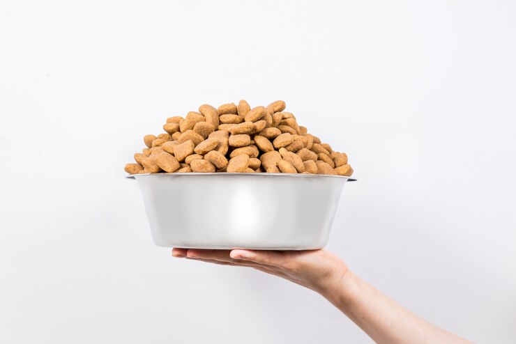 Tazza piena con uno scorrevole di alimento per animali domestici asciutto isolato su fondo bianco