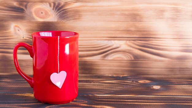 Tazza rossa con bustina di tè su fondo di legno