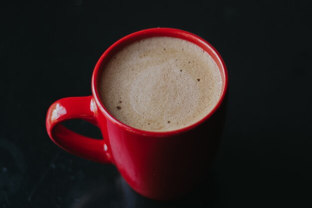 Tazza rossa con caffè mokachino in un bar su sfondo scuro