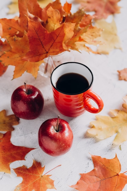 Tazza rossa con mele e foglie d'autunno