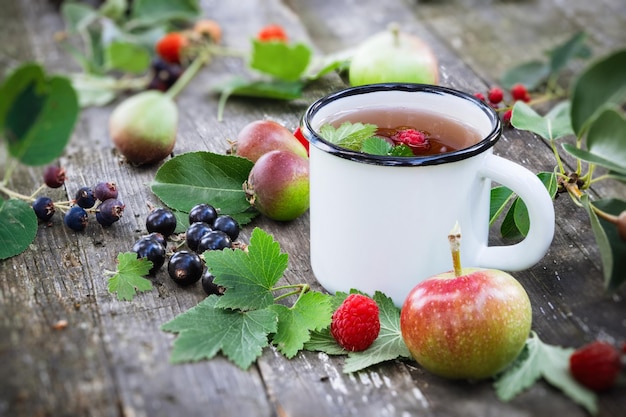 Tazza smaltata di tè alla frutta con mele pere lamponi e bacche di ribes nero