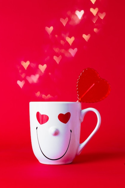 Tazza sorridente con lecca-lecca rosso e cuori bianchi. San Valentino concetto