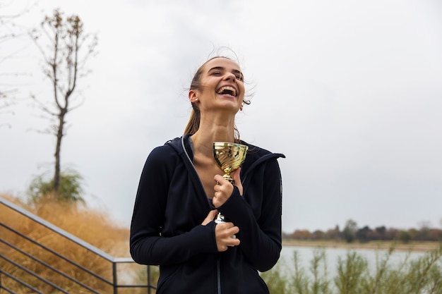 Tazza sportiva felice del trofeo dell&#39;oro della tenuta della giovane donna