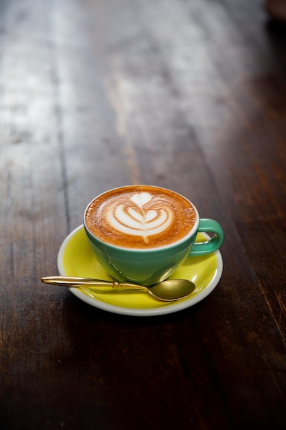 Tazza verde di cappuccino con latte art su fondo di legno