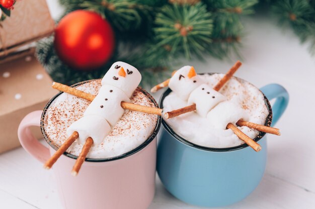 Tazze con cioccolata calda in cui gli uomini del marshmallow si rilassano. concetto di coppia