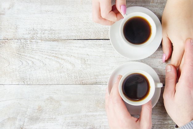 Tazze con un caffè nelle mani di uomini e donne Messa a fuoco selettiva