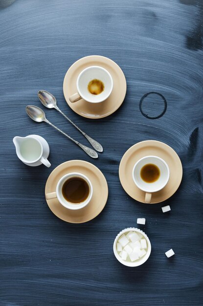 Tazze da caffè barattolo di latte e cucchiai su tavola con texture gesso sopra la vista