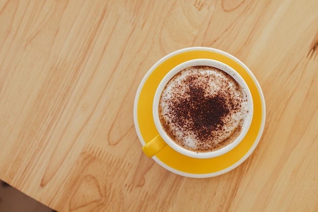 Tazze da caffè gialle sulla tavola di legno in caffè