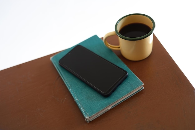 Tazze da caffè gialle, telefoni e libri sul tavolo di legno all'interno della casa.