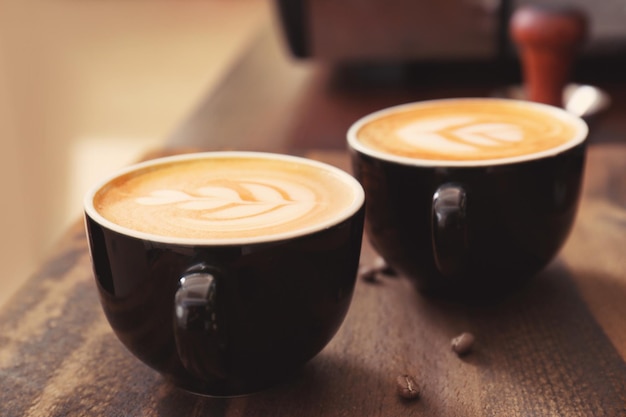 Tazze di caffè con latte art su fondo di legno