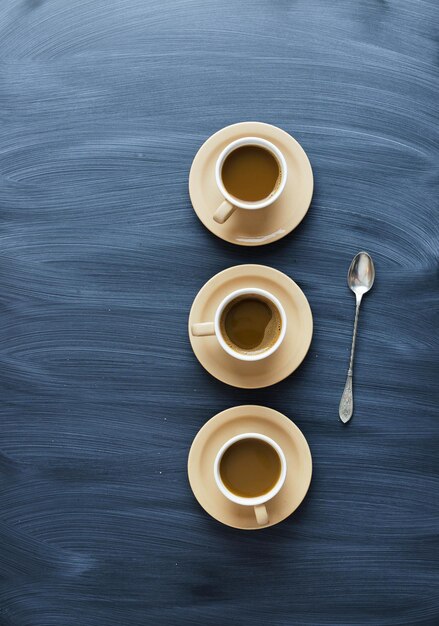 Tazze di caffè e un cucchiaio sopra la tabella strutturata del gesso sopra la vista