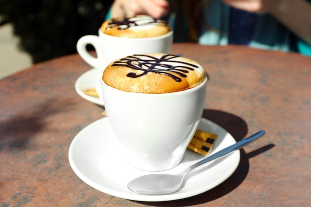 Tazze di cappuccino con chiave di violino su schiuma sul tavolo nella caffetteria