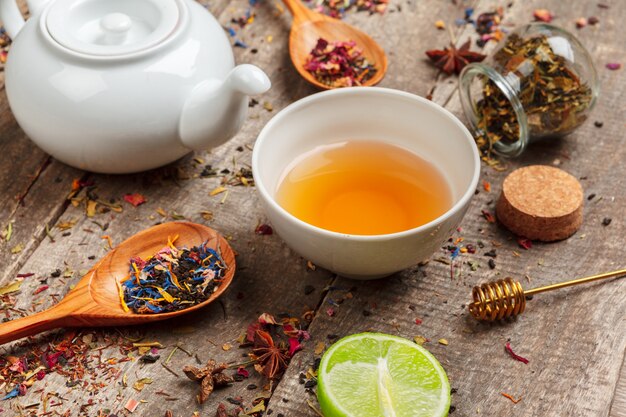 Tazze di tisana sana con cannella, fiori secchi di rosa e camomilla in cucchiai