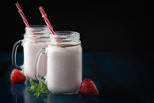 Tazze di vetro con delizioso milkshake alla fragola su un tavolo nero