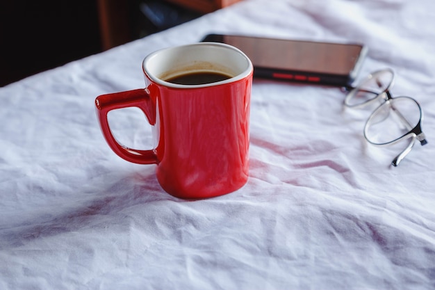 Tazze e bicchieri da caffè rossi con un telefono cellulare sul tavolo