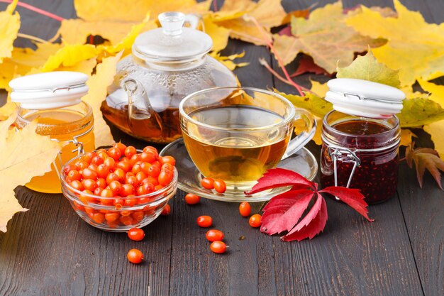 Tè a base di bacche di olivello spinoso sano per la salute delizioso, saturo di vitamine circondate da bacche e foglie di olivello spinoso per mantenere la salute nel corpo