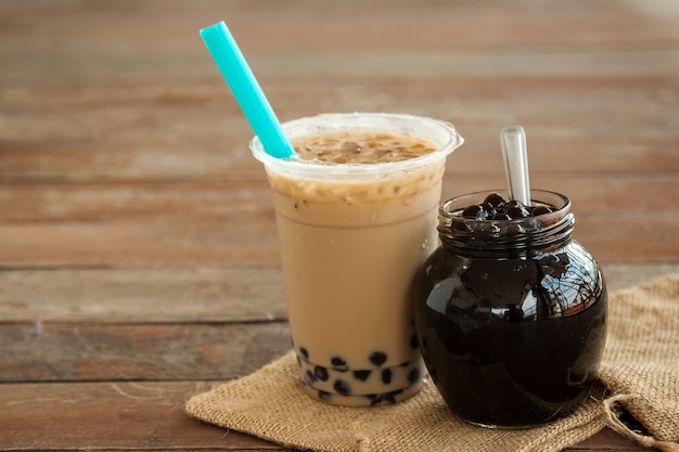 Tè al latte ghiacciato di Taiwan e bubble boba nel bicchiere di plastica e boba nel barattolo di vetro