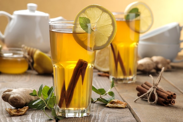 Tè al limone e una stecca di cannella con zenzero e menta in tazze di vetro su un tavolo di legno marrone. una bevanda calda. Bevanda autunnale o invernale.