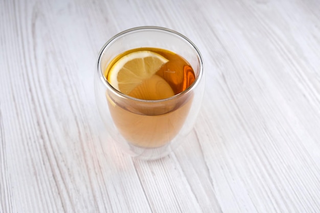 Tè al limone in una tazza di vetro su un tavolo di legno, spazio libero. Bevanda utile. Bevanda riscaldante