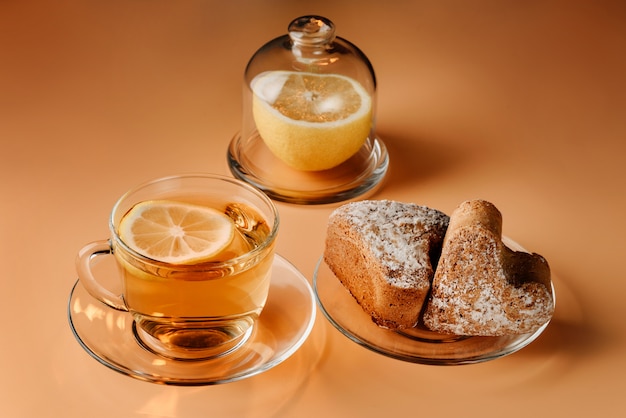 Tè al limone, muffin e limone su uno sfondo chiaro.