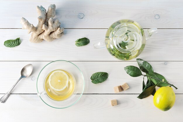 Tè al limone, zenzero e menta in un bicchiere Tazza, teiera e cucchiaino